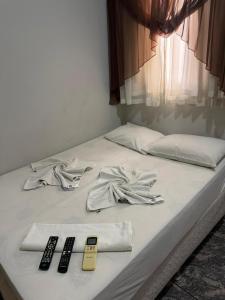 a bed with two remote controls and remotes on it at Hotel Telles in Hortolândia
