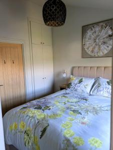 a bed with a blue comforter with flowers on it at Pudsey Loft Apartment in Pudsey
