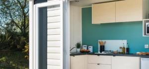 a kitchen with white cabinets and a blue wall at ZEcamping 3 étoiles familial pet friendly avec piscine et restaurant in Sandrans