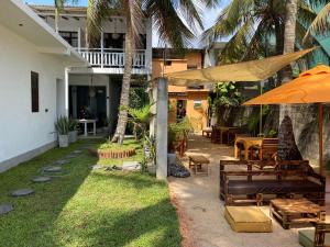 a patio with tables and chairs and an umbrella at Mandy House in Habaraduwa Central