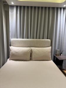 a bed with white pillows in front of a curtain at 1413 Home Suites Arezzo Place Davao in Davao City