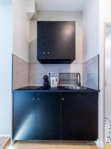 a kitchen with a black counter and a sink at Escapade à deux à 10mn de Paris in Gentilly +3 photos