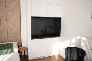 a kitchen with white cabinets and a black sink at Sauna Cafee & Beds in Český Těšín