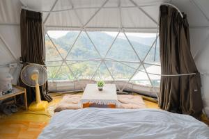 a room with a bed and a large window at ลักษณ์ภูชี้ฟ้า 2 แบบโดม in Ban Seng Choi