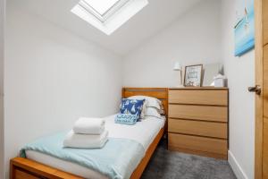 a small bedroom with a bed and a wooden dresser at Charlotte Cottage - Minutes from Poole Park, with Feature Log Burner in Poole