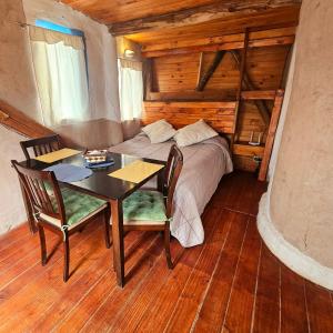 a bedroom with a bed and a table and chairs at ECOCABAÑAS CERRO ARKO in Mendoza