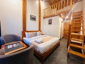 a bedroom with a bed and a staircase and a chair at The Grand Dwaper A- Luxury Rooms & Parking Walking Distance From Mall Road in Mussoorie