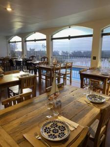 a dining room with a wooden table with plates and glasses at Restau de Marambaia in Barra de Guaratiba