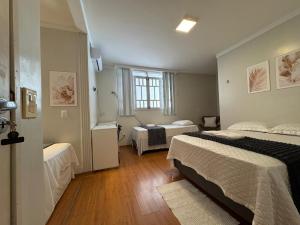 a hotel room with two beds and a window at Pousada Hospedar Imperial in Campina Grande