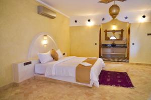 a bedroom with a large white bed in a room at Hotel Sunset Palace in Merzouga