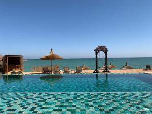 a swimming pool with chairs and umbrellas on the beach at Dakhla South Bay, WorldHotels Distinctive in Dakhla