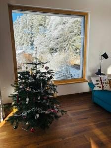 a christmas tree in a living room with a window at Eco-Chalet Matschiedl in Tratten