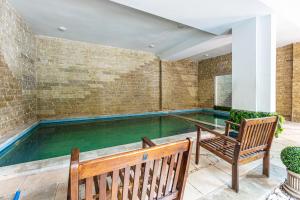 a swimming pool in a house with a bench and a chair at Hotel Golden Spirit in Băile Herculane