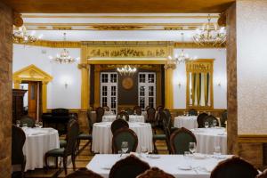 a dining room with white tables and chairs and chandeliers at Dwór Lisewo in Lisewo