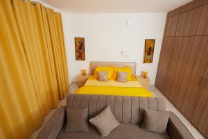 a bedroom with a large bed with yellow sheets and a couch at La Villa Tombouctou in Bingerville +35 photos