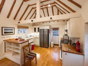 a kitchen with white cabinets and a black refrigerator at Leacon Hall Lodge in Orlestone