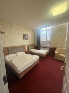 a bedroom with two beds and a red carpet at Zolotoi Drakon Hotel in Almaty