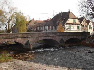 un pont en pierre sur une rivière dans une ville dans l'établissement Hotel Relais d'ISSENHEIM Table d'hôtes, à Issenheim