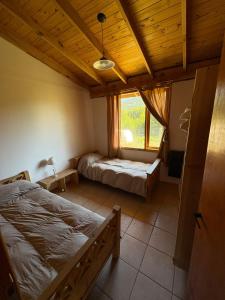 a bedroom with two beds and a window at Complejo Cabañas Ganesh in Lago Meliquina