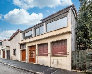 an old brick building with large windows on a street at Escapade à deux à 10mn de Paris in Gentilly