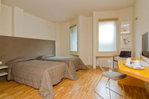 a hotel room with two beds and a desk and a desk at Stile Libero in Orio al Serio