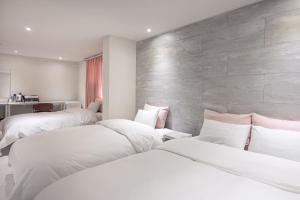 two beds in a room with white sheets and pink pillows at MoMo Juice Busan Haeundae in Busan