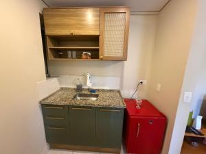 a small kitchen with a sink and a red refrigerator at Hotel Flat Biena Parque Ibirapuera 810 incluso estacionamento in São Paulo