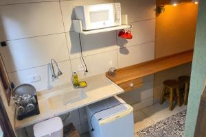 a small kitchen with a sink and a microwave at Vilarejo hospedagem- Espaço Beco Carioca in Ilha do Mel