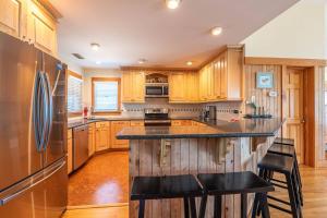 a kitchen with wooden cabinets and a island with bar stools at Run-A-Way Bay - Duck, Sanderling, Oceanfront, Ocean View, Hot Tub, Community Pool, Tennis in Duck