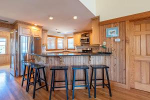 a kitchen with wooden cabinets and bar stools at Run-A-Way Bay - Duck, Sanderling, Oceanfront, Ocean View, Hot Tub, Community Pool, Tennis in Duck