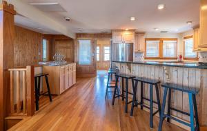a kitchen with wooden cabinets and bar stools at Run-A-Way Bay - Duck, Sanderling, Oceanfront, Ocean View, Hot Tub, Community Pool, Tennis in Duck +50 photos