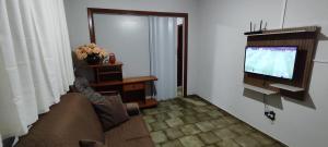 a living room with a couch and a flat screen tv at Habitaflex Casa No Centro de Urupês in Urupês