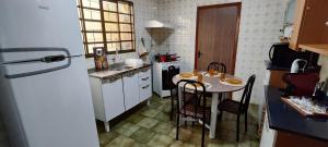 a small kitchen with a table and a refrigerator at Habitaflex Casa No Centro de Urupês in Urupês