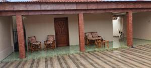 a porch with chairs and a door on a house at Habitaflex Casa No Centro de Urupês in Urupês