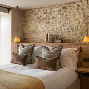 a bedroom with a large bed with four pillows at Louma Country Hotel in Wootton Fitzpaine