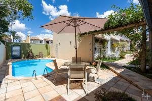 a patio with a table and an umbrella next to a pool at CasinhaPiri in Pirenópolis