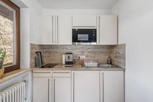 a kitchen with white cabinets and a microwave at Gaestehaus Florian - Ferienwohnungen in Grainau
