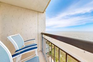 a balcony with two chairs and the ocean at OIB74 Kat Cove 2 in Ocean Isle Beach