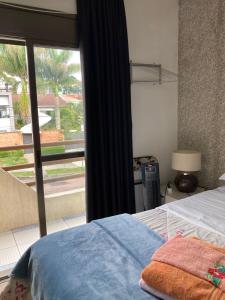 a bedroom with a bed and a window with a view at Hospedagem Three Little Birds in Curitiba
