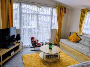 a living room with a couch and a table at Seascape Caravan in Kinmel Bay