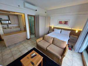 a bedroom with a bed and a couch and a kitchen at Tropical Executive Flat Vista Maravilhosa do Rio in Manaus