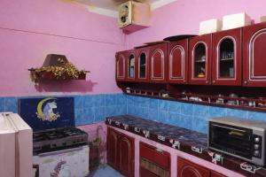 a kitchen with red cabinets and a purple wall at Mostafa Gest House in Asyut