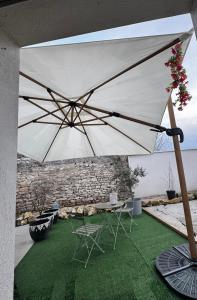 Ein großer weißer Sonnenschirm über einem Tisch und Stühlen in der Unterkunft RevaCasa in Magny-Saint-Médard