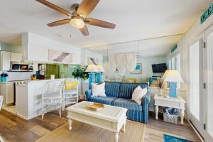a living room with a blue couch and a kitchen at OIB88 PierSide Paradise in Ocean Isle Beach