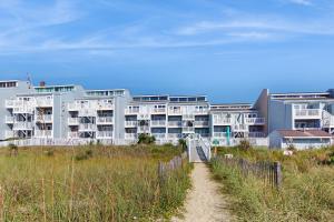 a building on the beach with a path in front of it at OIB88 PierSide Paradise in Ocean Isle Beach