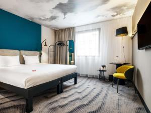 a hotel room with a bed and a yellow chair at Hotel Ibis Krakow Centrum in Krakow