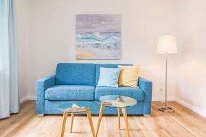 a blue couch in a living room with two tables at Ferienhaus Ankerplatz in Timmendorfer Strand