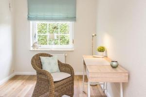 a wicker chair and a table in a room with a window at Ferienhaus Ankerplatz in Timmendorfer Strand +14 photos