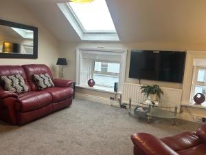 a living room with a leather couch and a flat screen tv at Tranquility in Longford