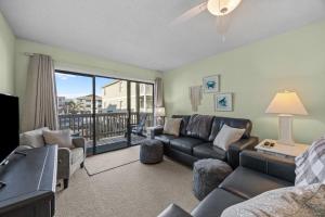 a living room with a couch and a table and a window at OIB90 Endless Summer in Ocean Isle Beach
